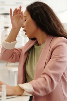 woman sitting at desk with computer while sneezing