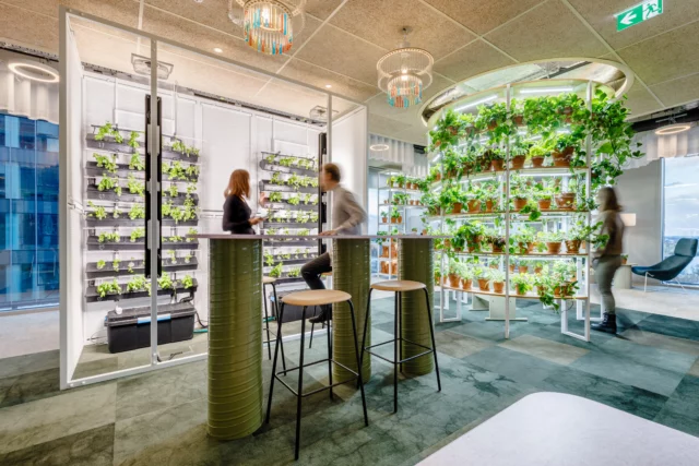 Two people standing at a table with ceiling-high shelves filled with plants behind them